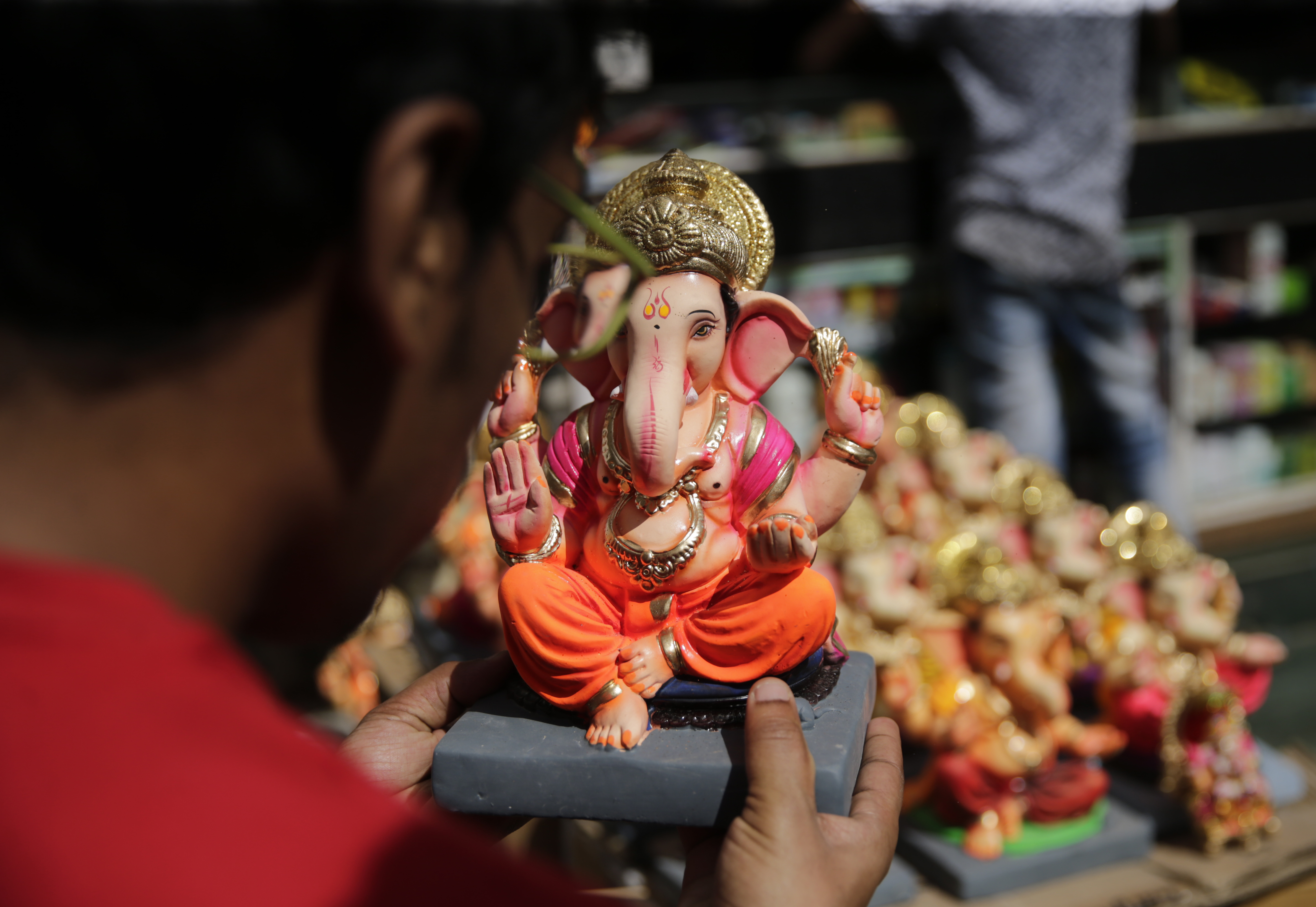 A devotee looks at an idol of elephant-headed Hindu god Ganesha displayed for sale at a worship during Ganesh Chaturthi festival celebrations in Mumbai - AP