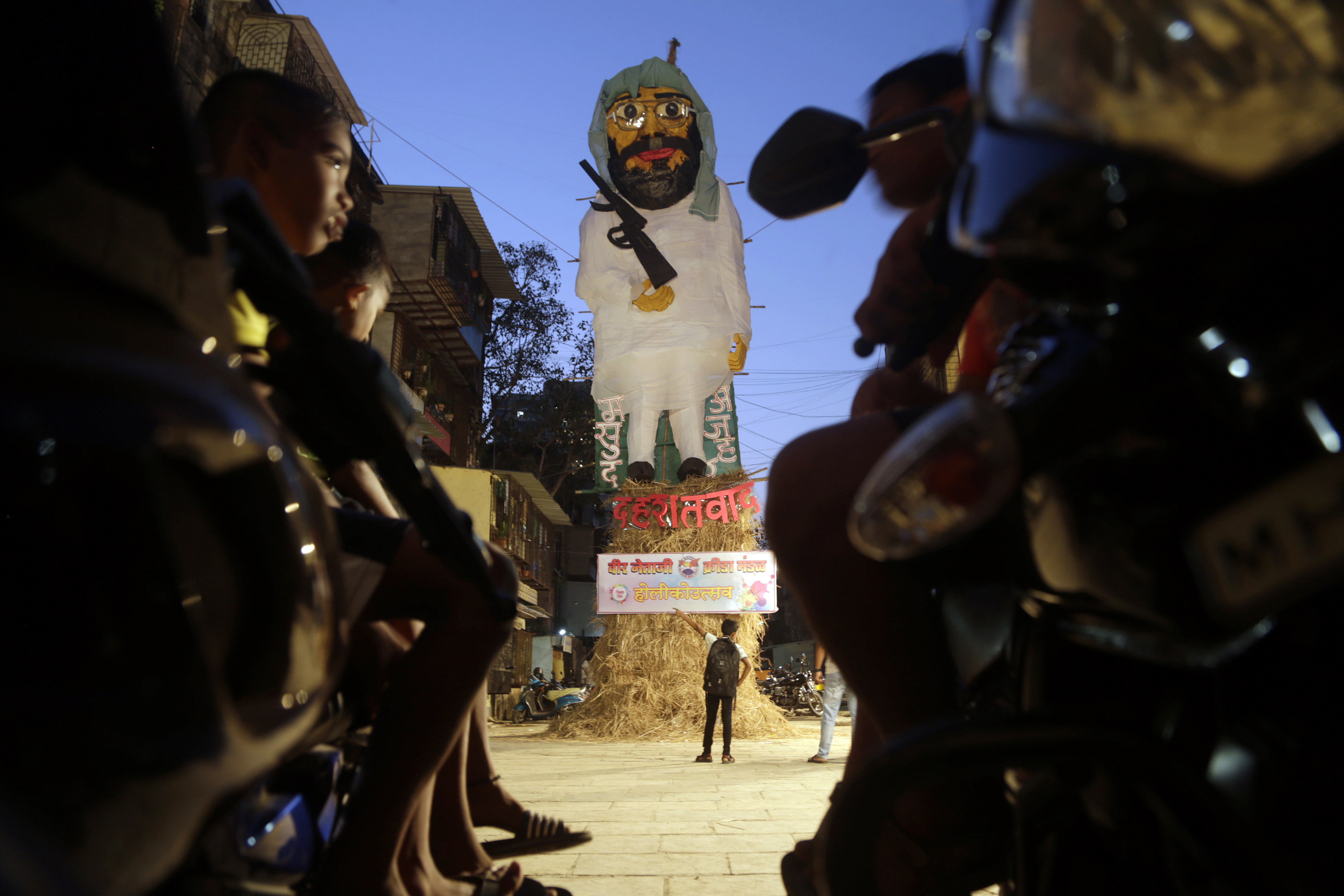 A boy points to an effigy made in the likeness of Jaish-e-Mohammad chief Masood Azhar to be lit as part of the Hindu festival of Holika Dahan in Mumbai - AP