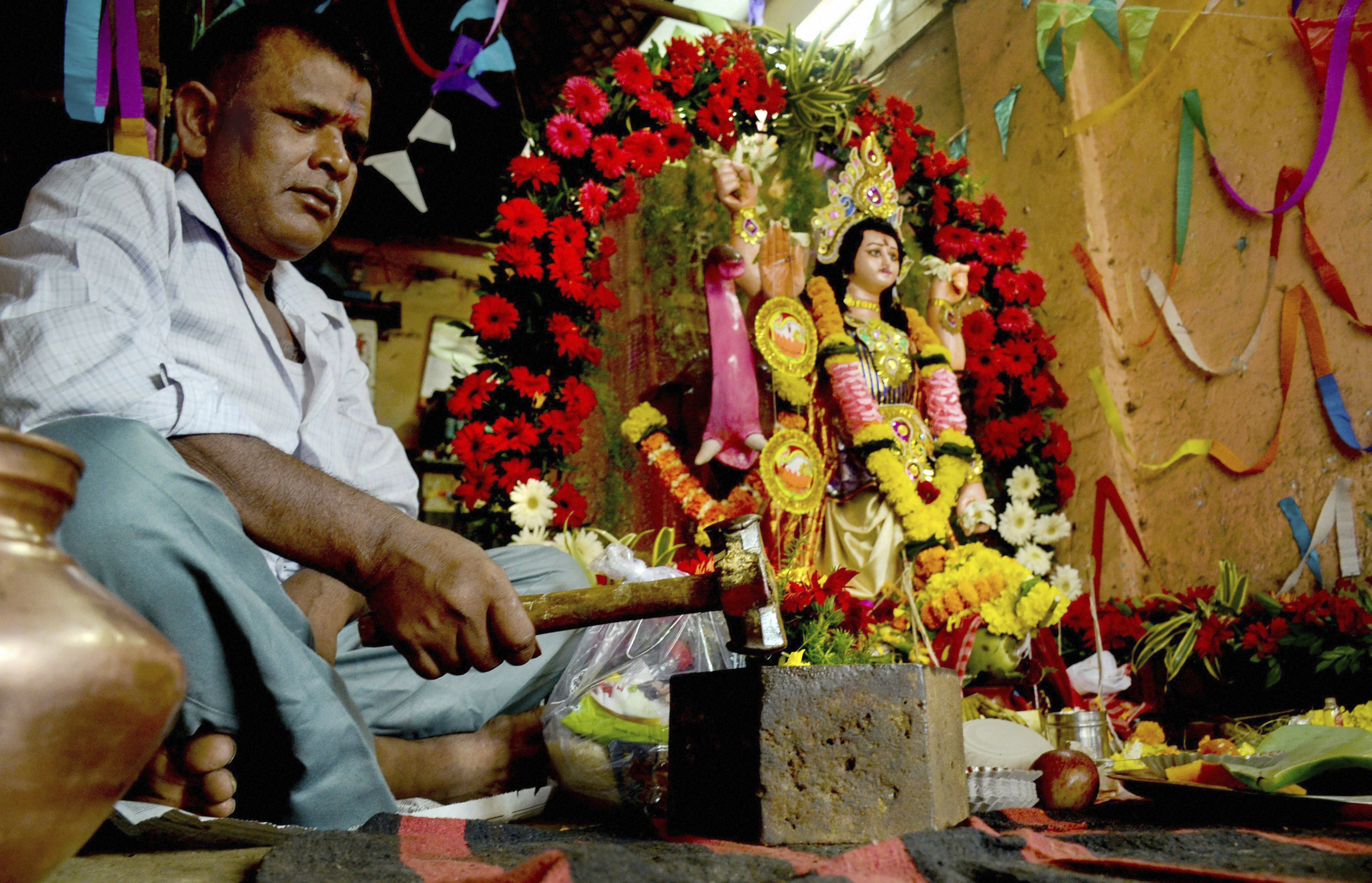 A workers worships his equipments on the occasion of Vishwakarma Puja at Vashi, Navi Mumbai - PTI