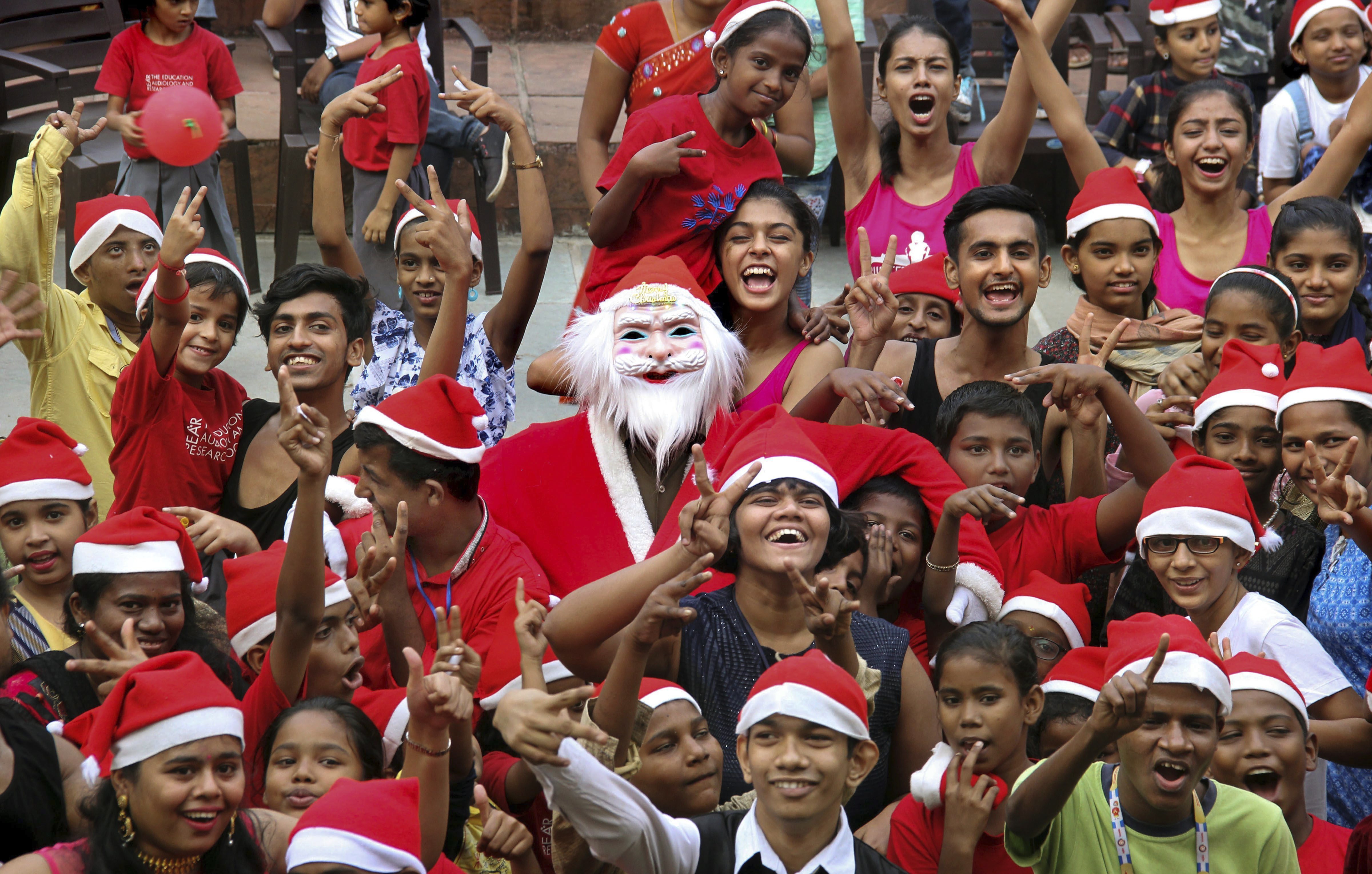 An artist dressed as Santa Claus poses with children from various NGOs during Christmas celebrations, in Mumbai - PTI