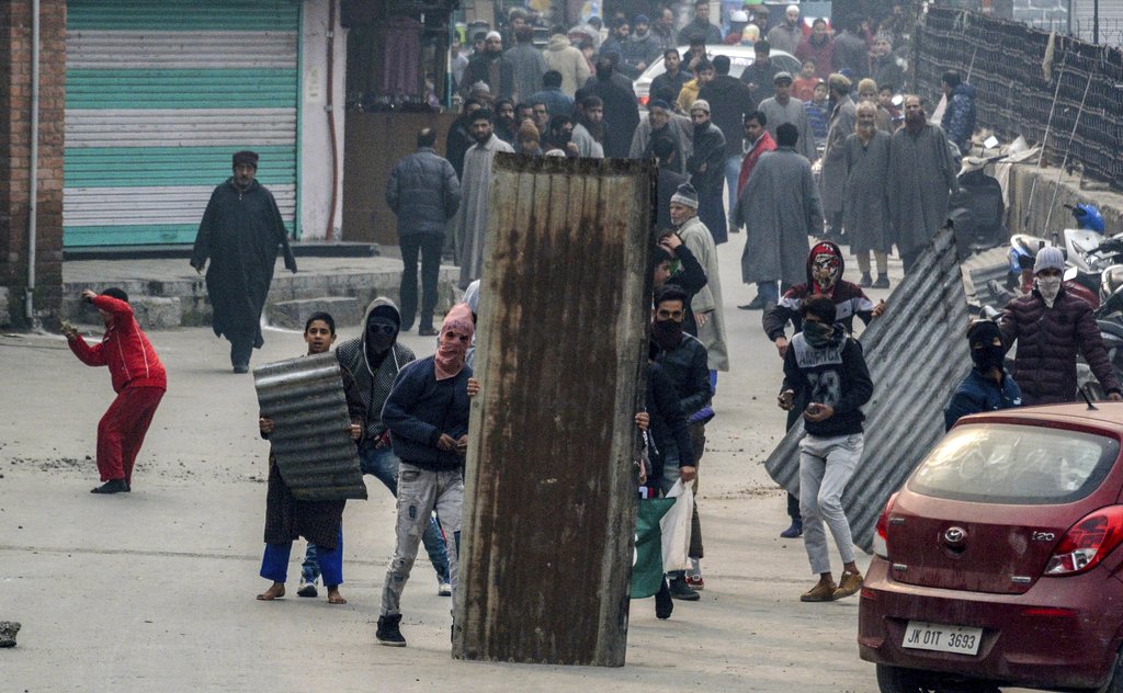 Youth throw stones at the police during clashes between police and protesters in Srinagar - PTI