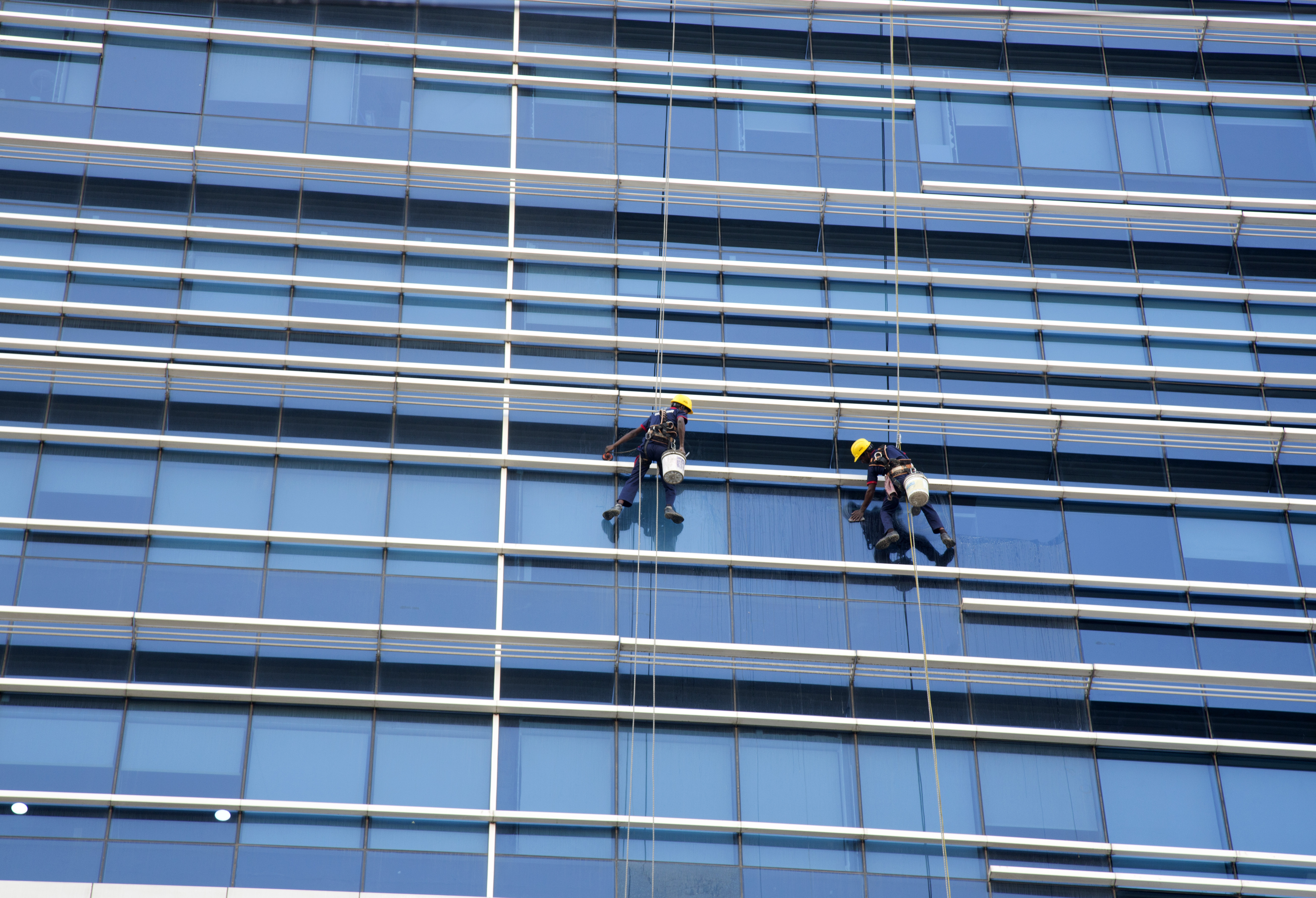 Window cleaners work on glass panes of a building in Hyderabad, India - AP