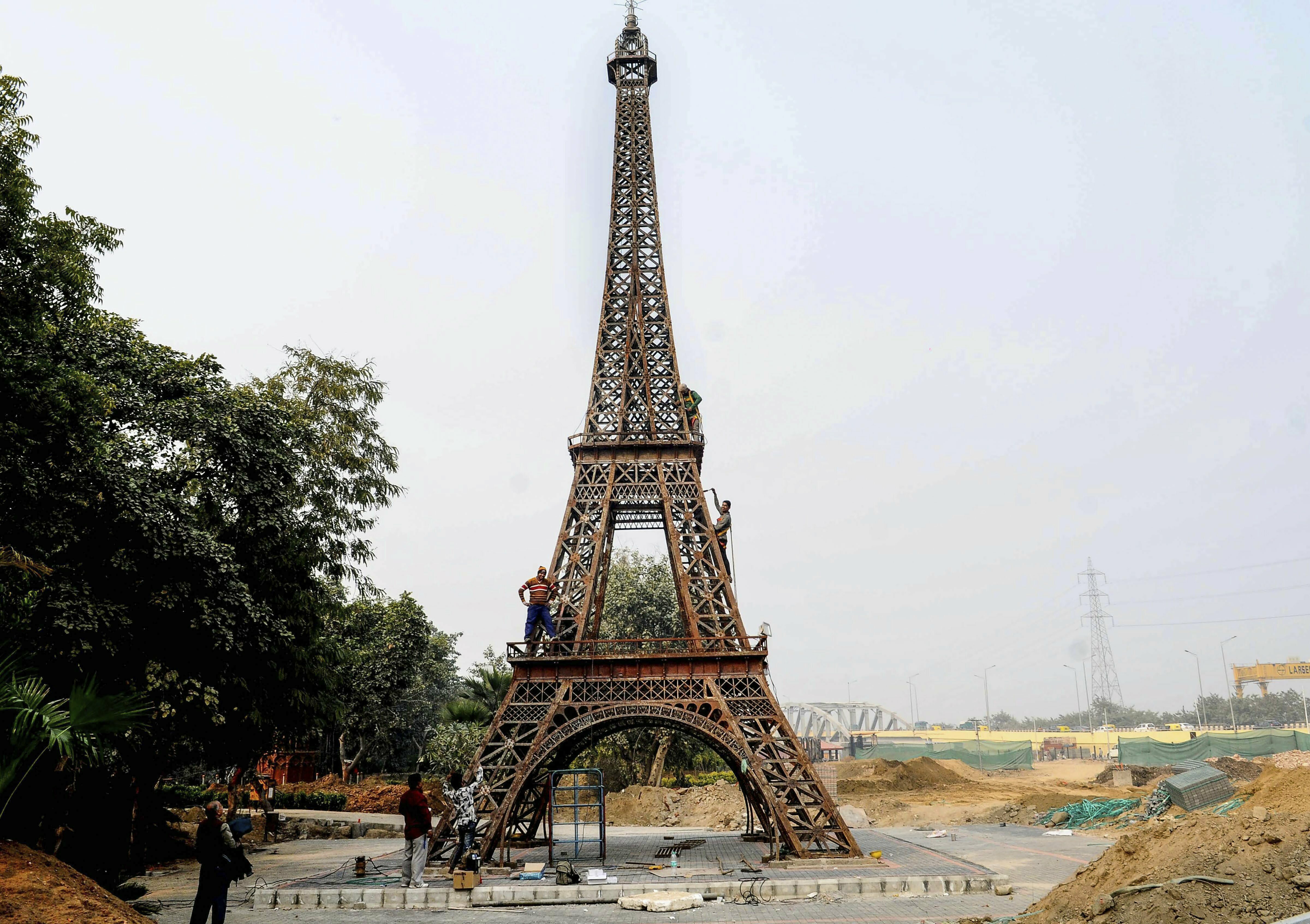 Workers carry out work at the replica of Eiffel Tower at a theme park featuring the replicas of world's seven wonders, in New Delhi - PTI