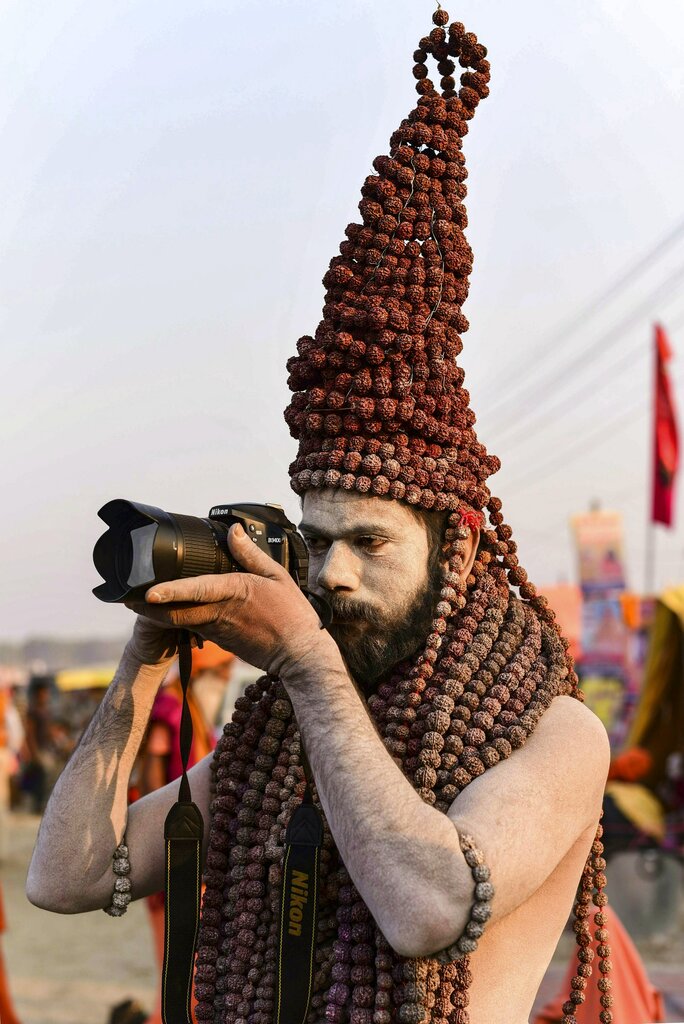 A Naga sadhu wears rudraksha garlands as she takes photo with a camera during Kumbh Mela festival 2019, in Allahabad - PTI
