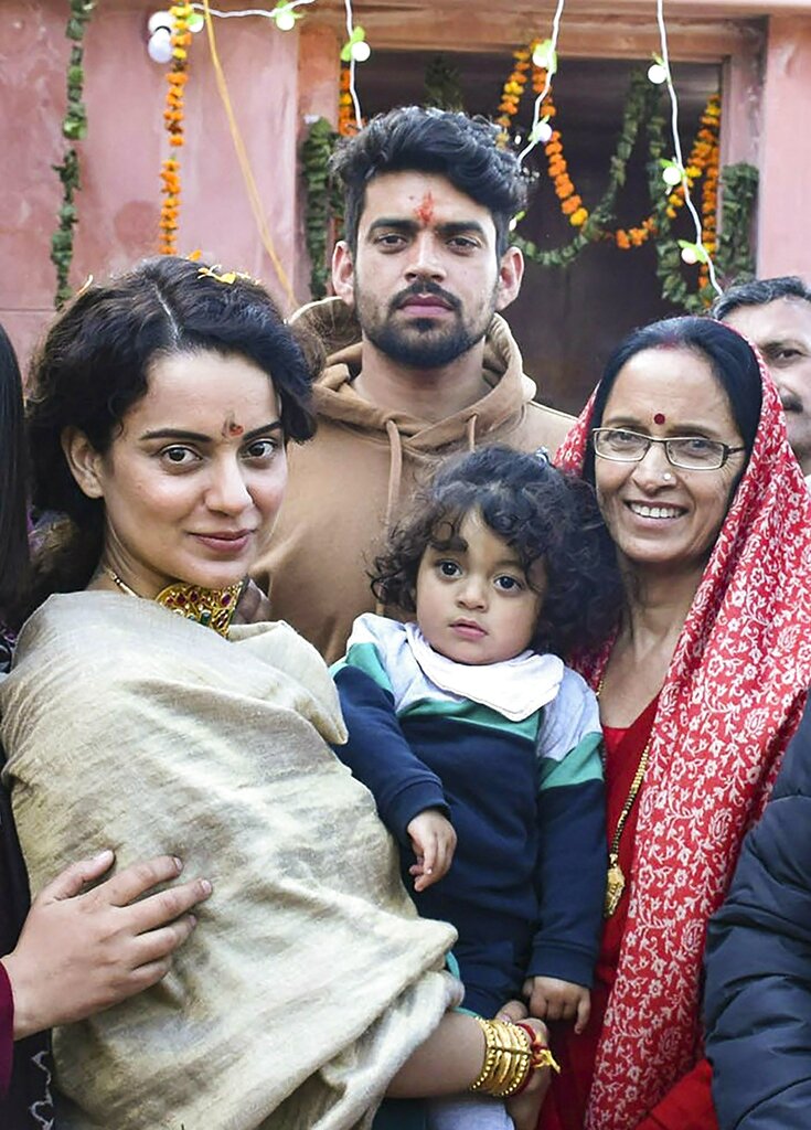 Bollywood actor Kangana Ranaut poses for photos with her family members after paying obeisance at a newly-built temple, in Mandi - PTI