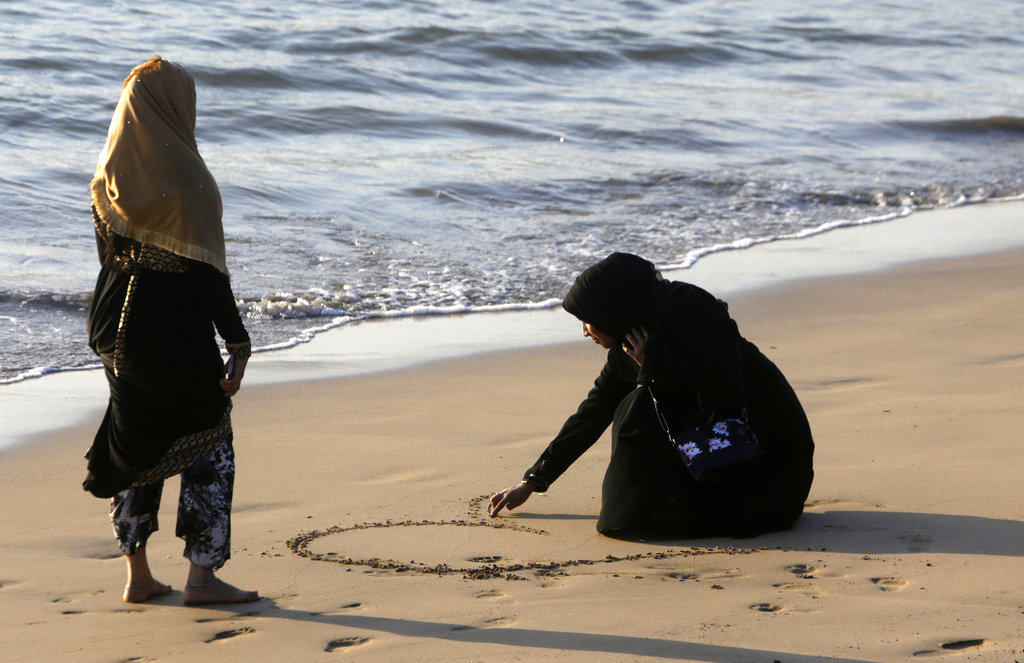 An Indian Muslim woman draws a shape of heart at a beach in Mumbai - AP