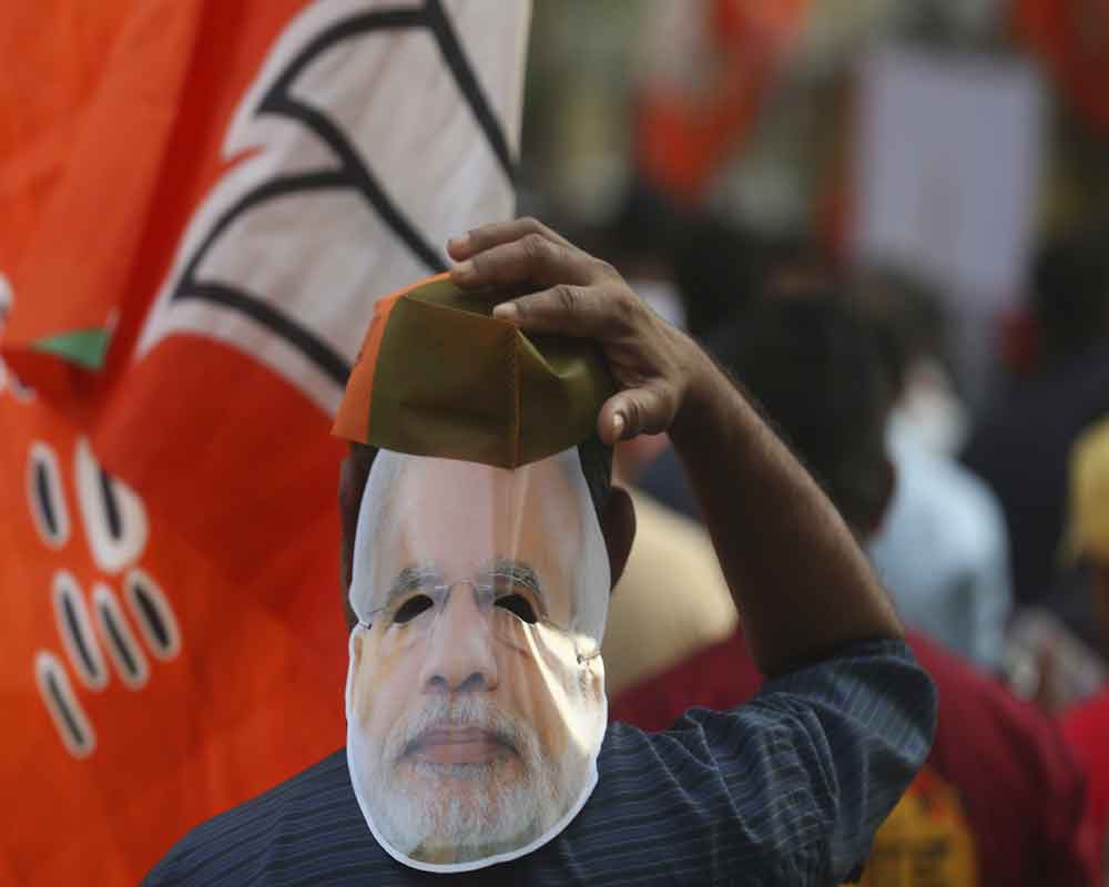 A supporters of India's Bharatiya Janata Party (BJP) wearing a mask of Prime Minister Narendra Modi participates in an election campaign rally in Mumbai - AP