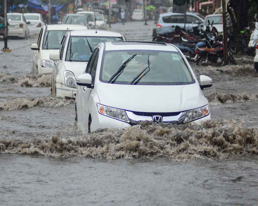 Vehicles wade across a waterlogged street following monsoon rainfall, in Vijaywada - PTI