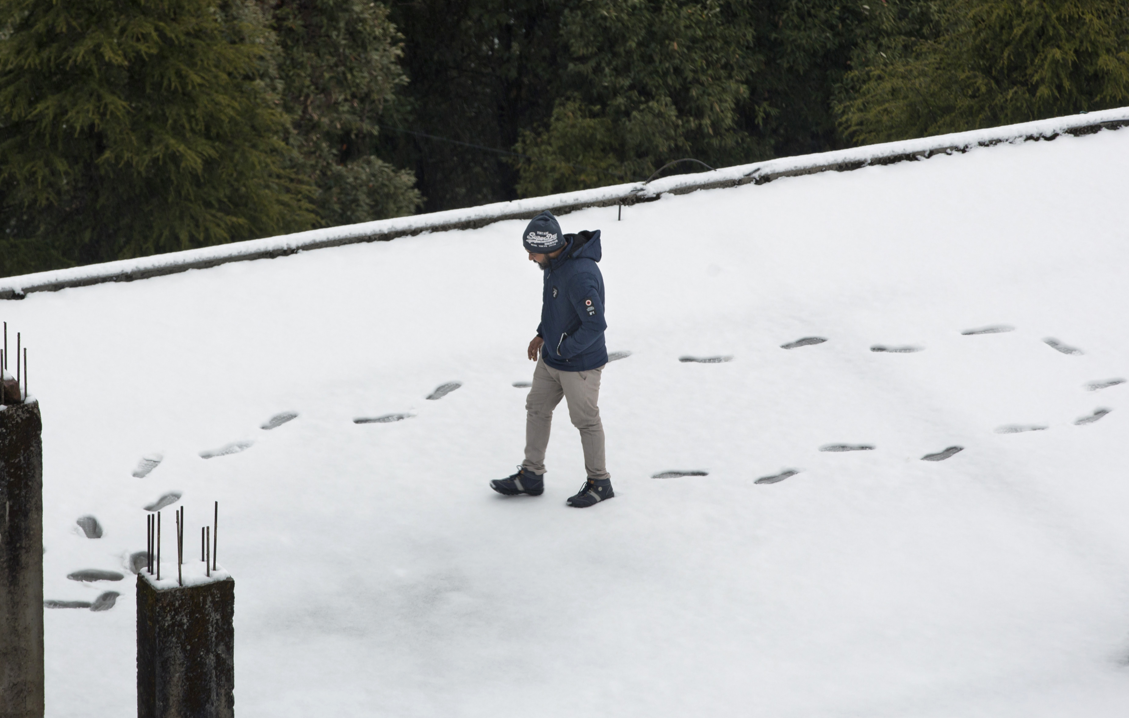 A man walks on a snow-covered rooftop in Dharmsala - AP