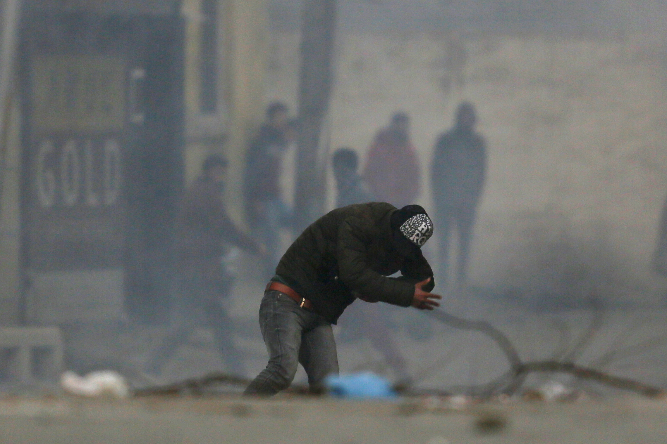 A Kashmiri protester ducks to avoid tear smoke shell during a clash with Indian paramilitary soldiers in Srinagar - AP