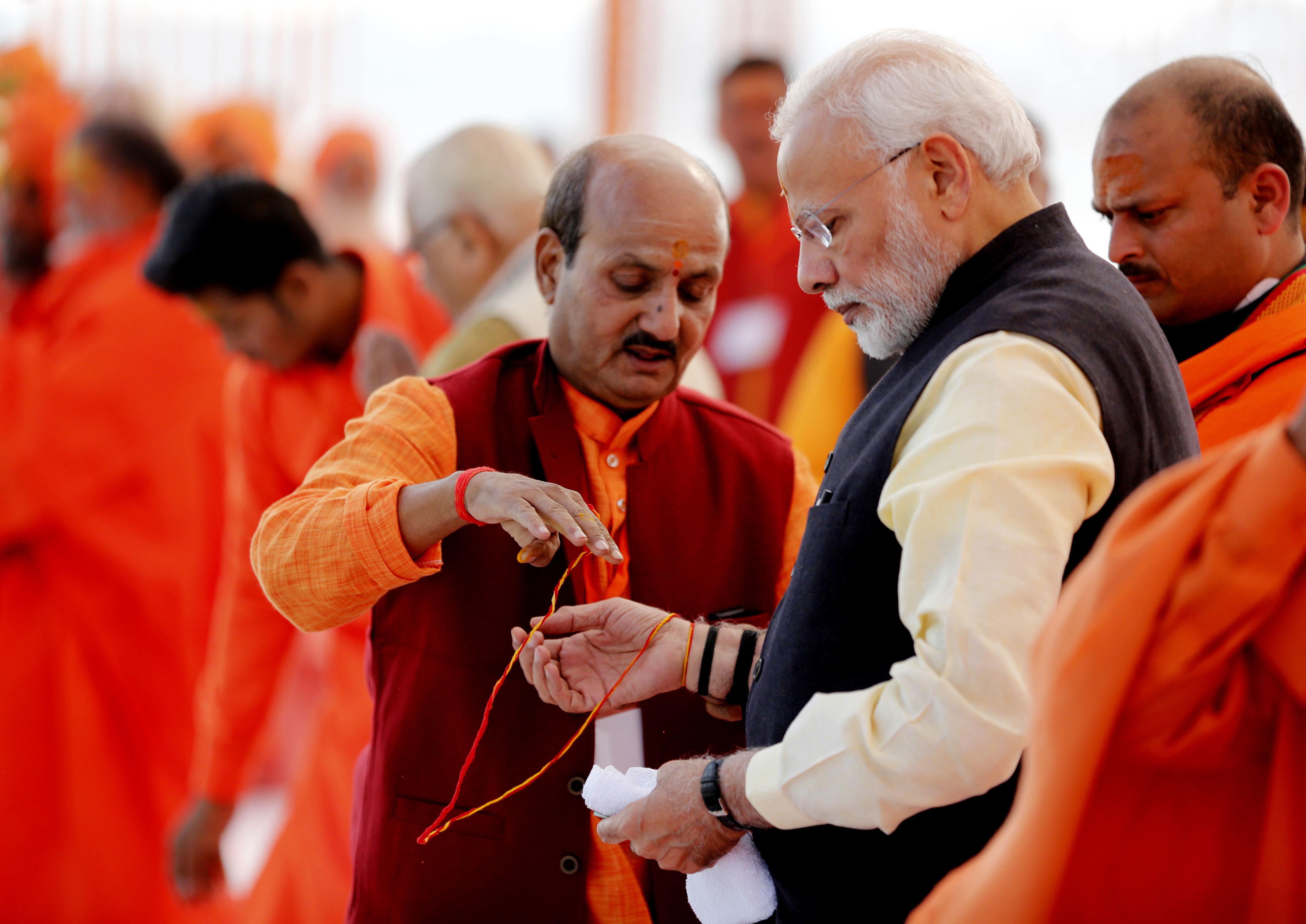 A Hindu holy man ties a 'sacred thread' on the wrist of Indian Prime Minister Narendra Modi, at Sangam, the confluence of the Rivers Ganges and Yamuna, at Allahabad, India - AP