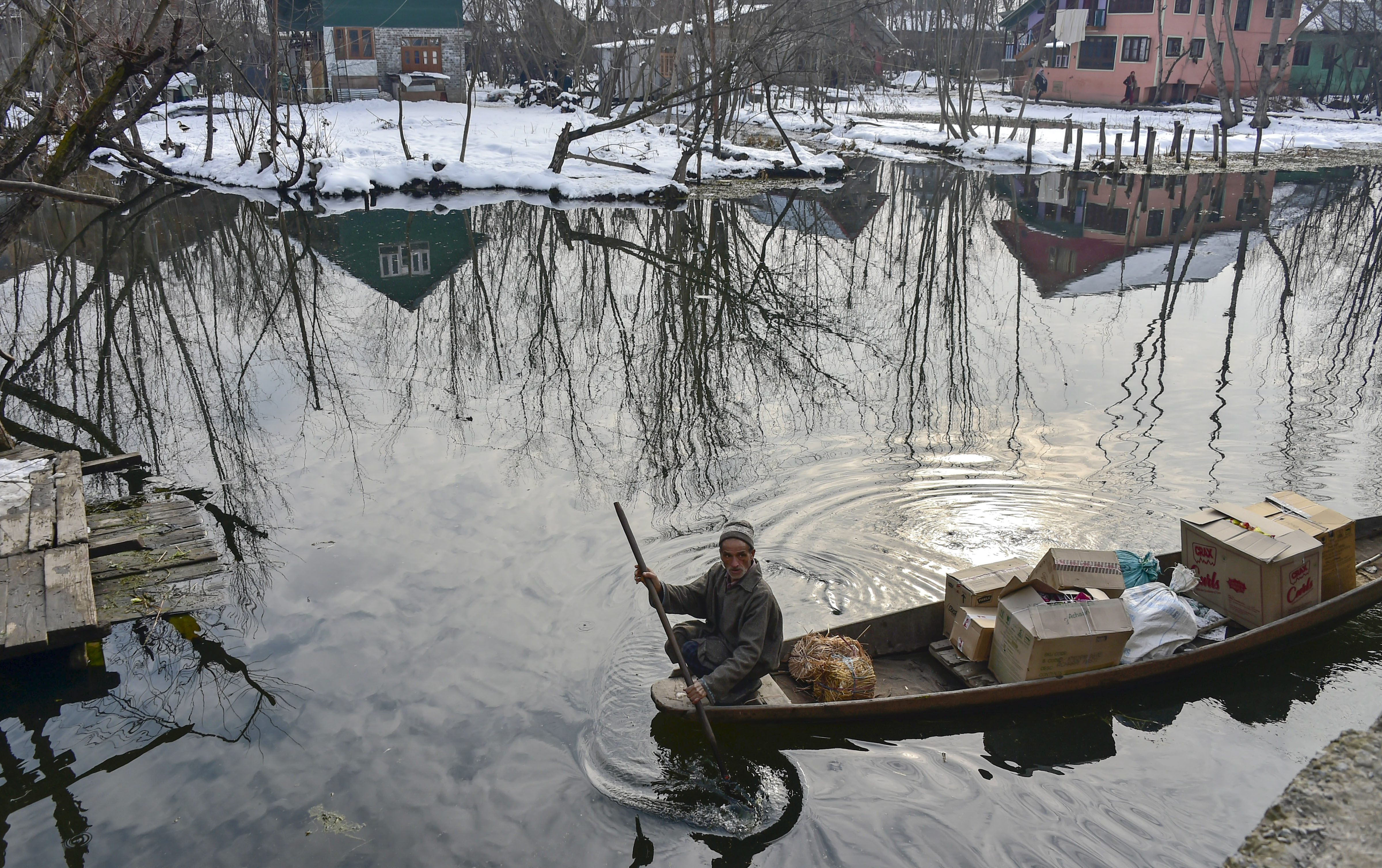 A vendor takes his boat through an area covered by snow on a cold, winter morning, in the interiors of Dal Lake in Srinagar - PTI
