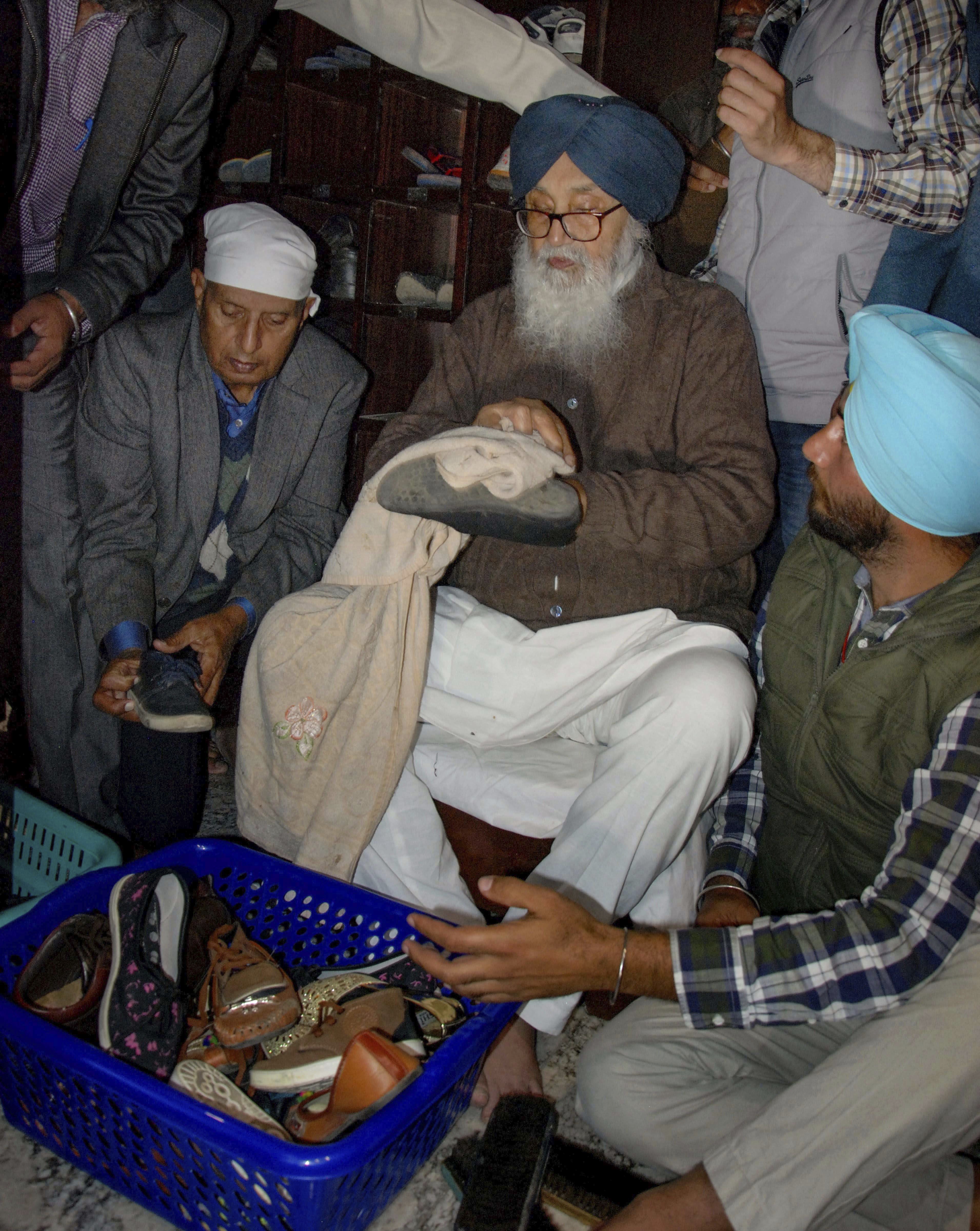 SAD party patron Parkash Singh Badal cleans shoes at Jora Ghar of Golden Temple, in Amritsar - PTI