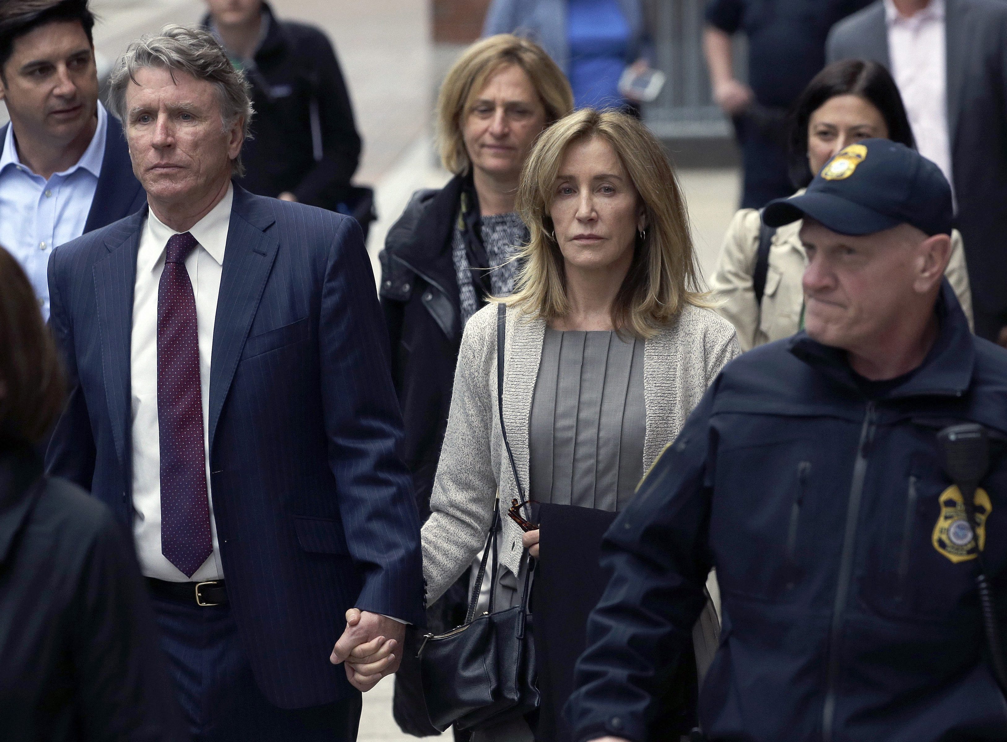 Felicity Huffman, center, departs federal court with her brother Moore Huffman Jr., left in Boston - PTI
