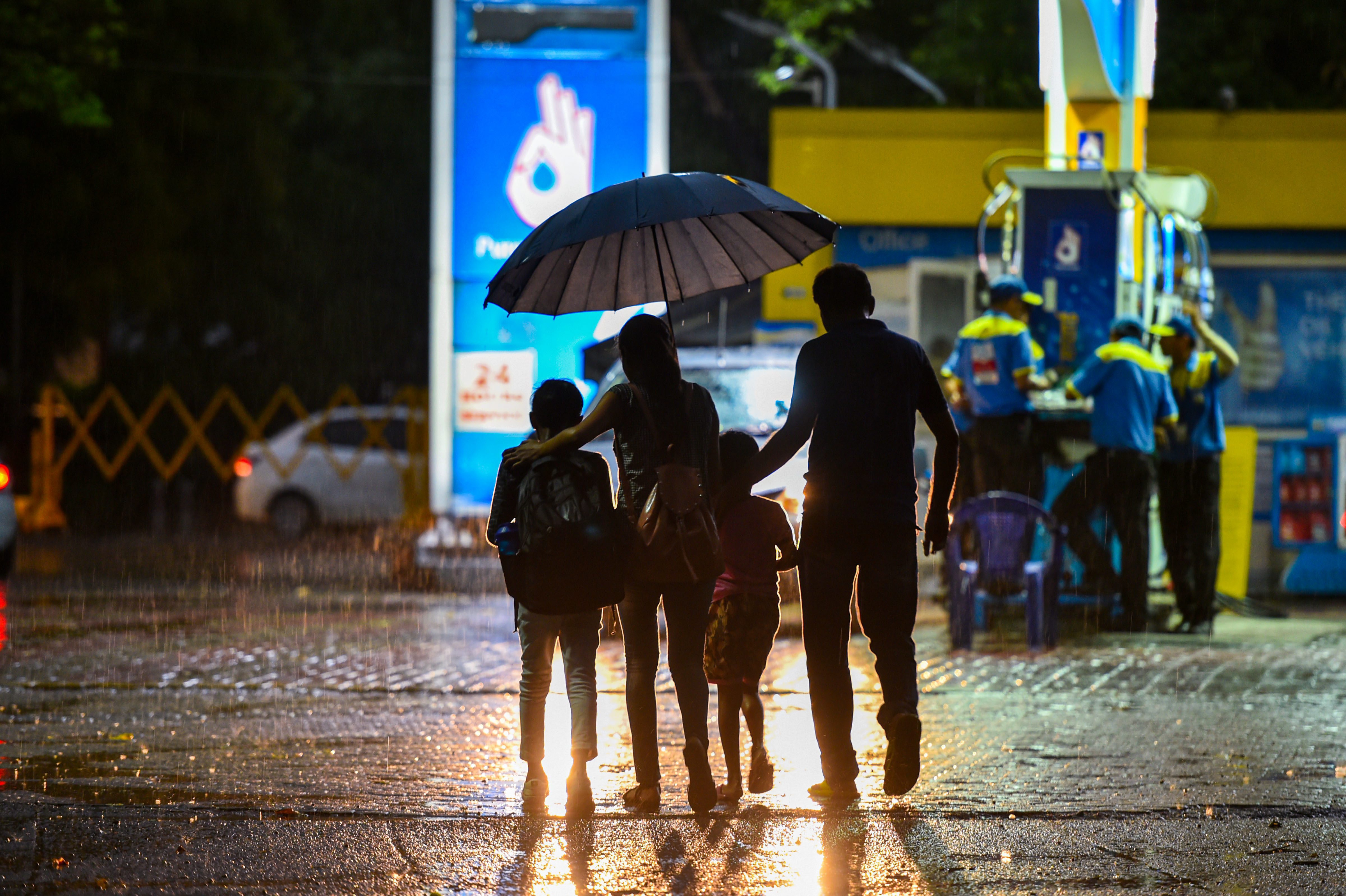 A family crosses a road during a drizzle, in New Delhi - PTI