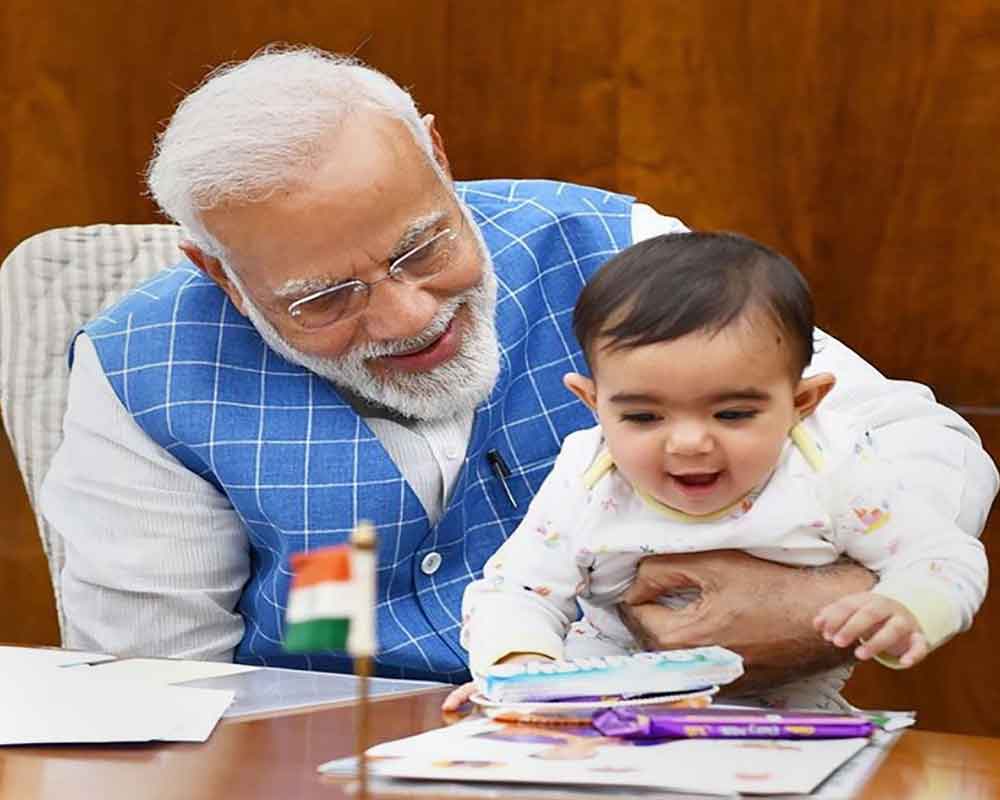Prime Minister Narendra Modi plays with a child at Parliament - PTI