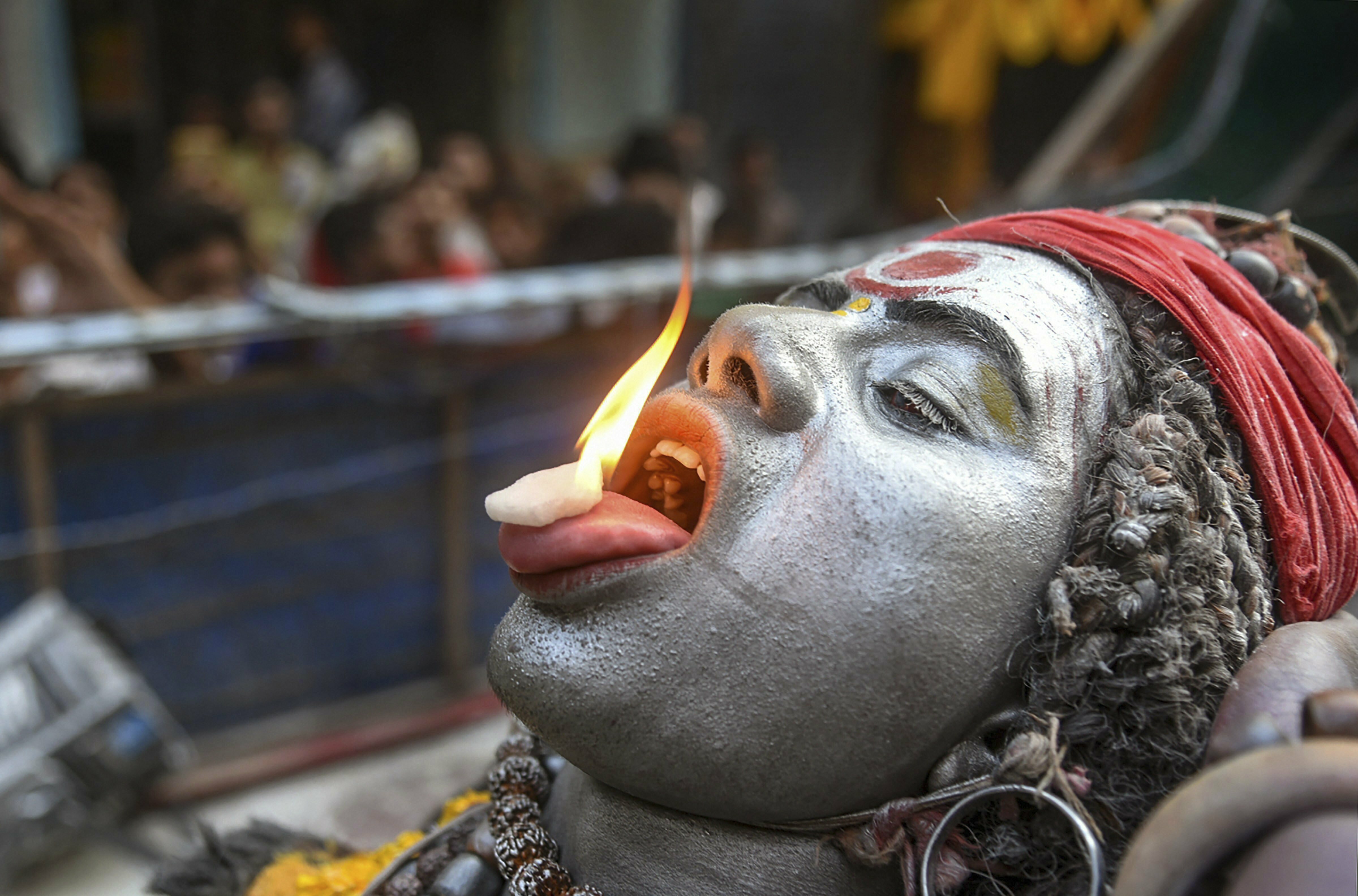 A devotee places a burning camphor on his tongue as he participates in a Shiv Baraat procession on the occasion of 'Maha Shivratari' festival, in Allahabad - PTI