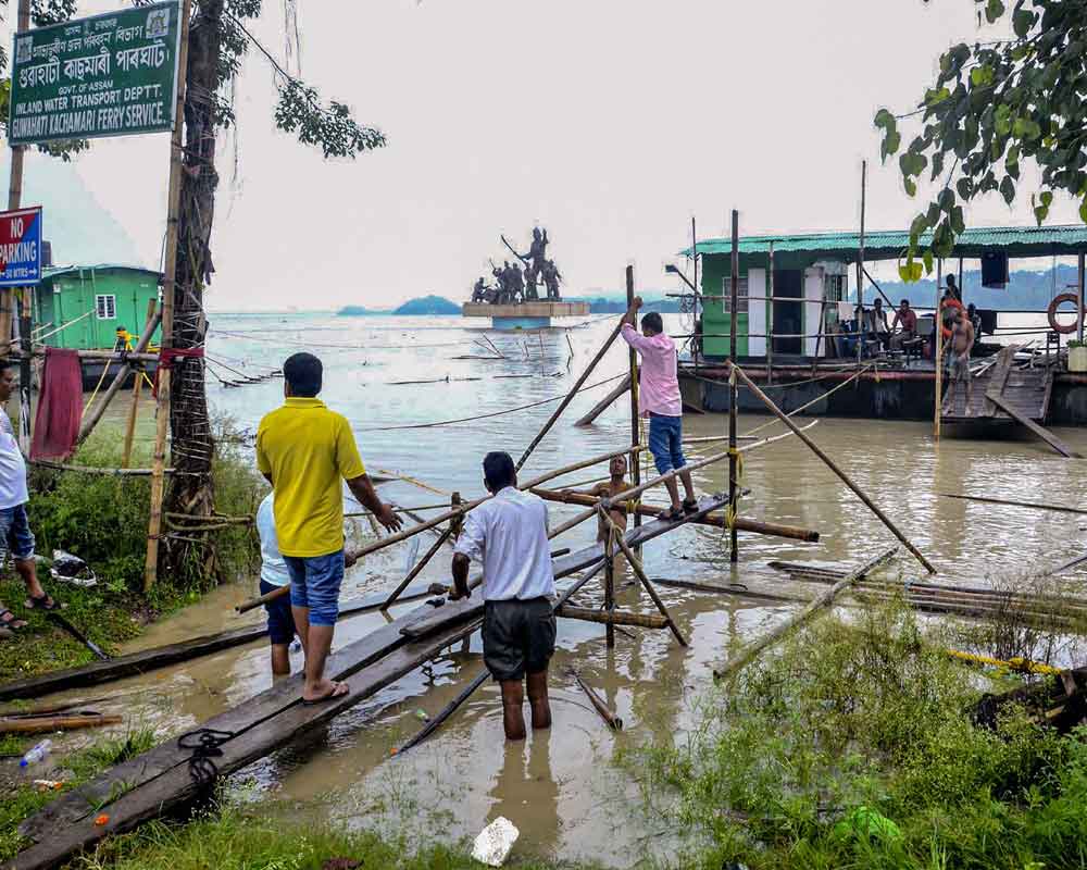 Workers construct a bamboo structure to reach a ferry on the swelled Brahmaputra river following heavy monsoon rain, in Guwahati - PTI
