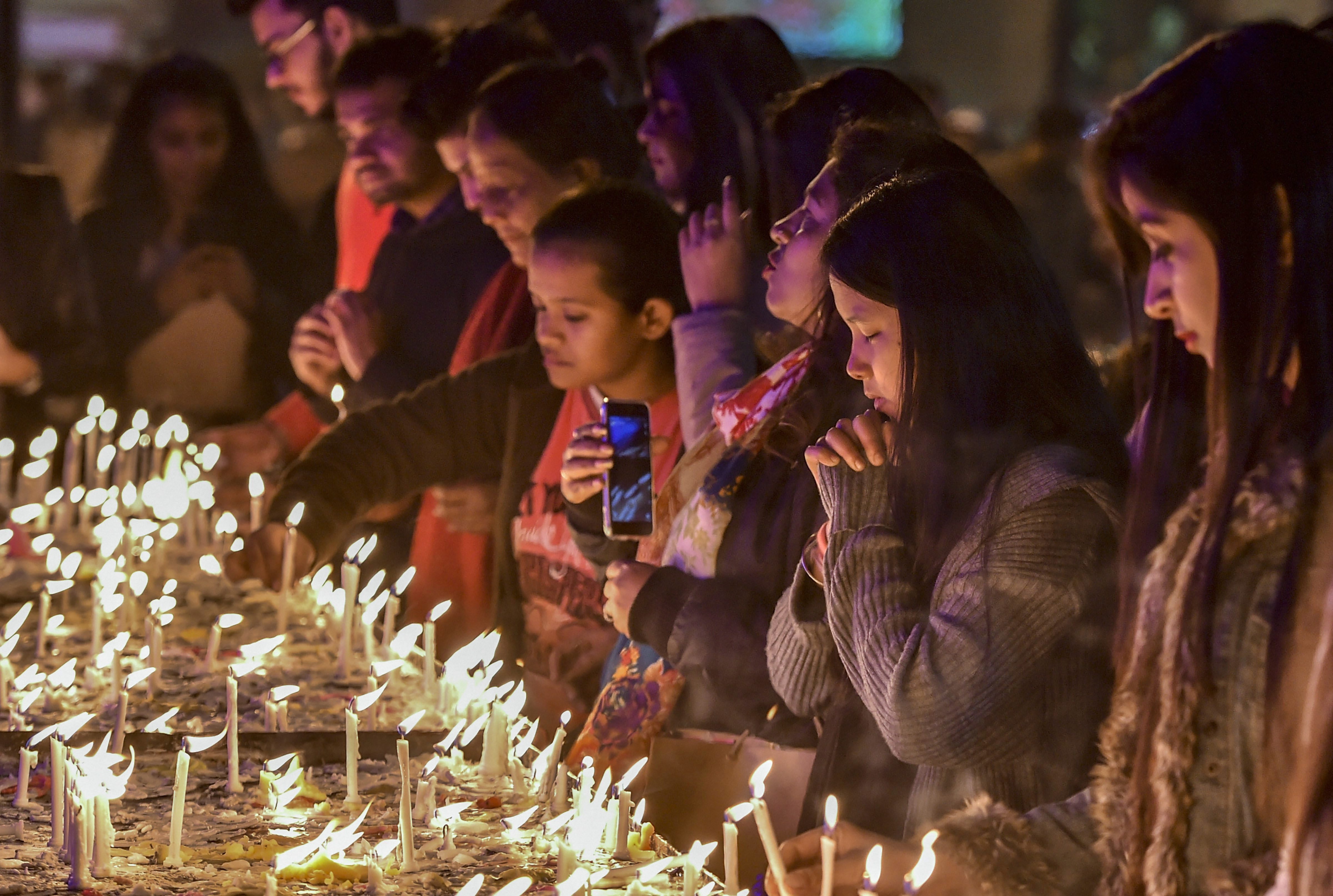 People light candles at the Sacred Heart Cathedral on the eve of Christmas Day in New Delhi - AP