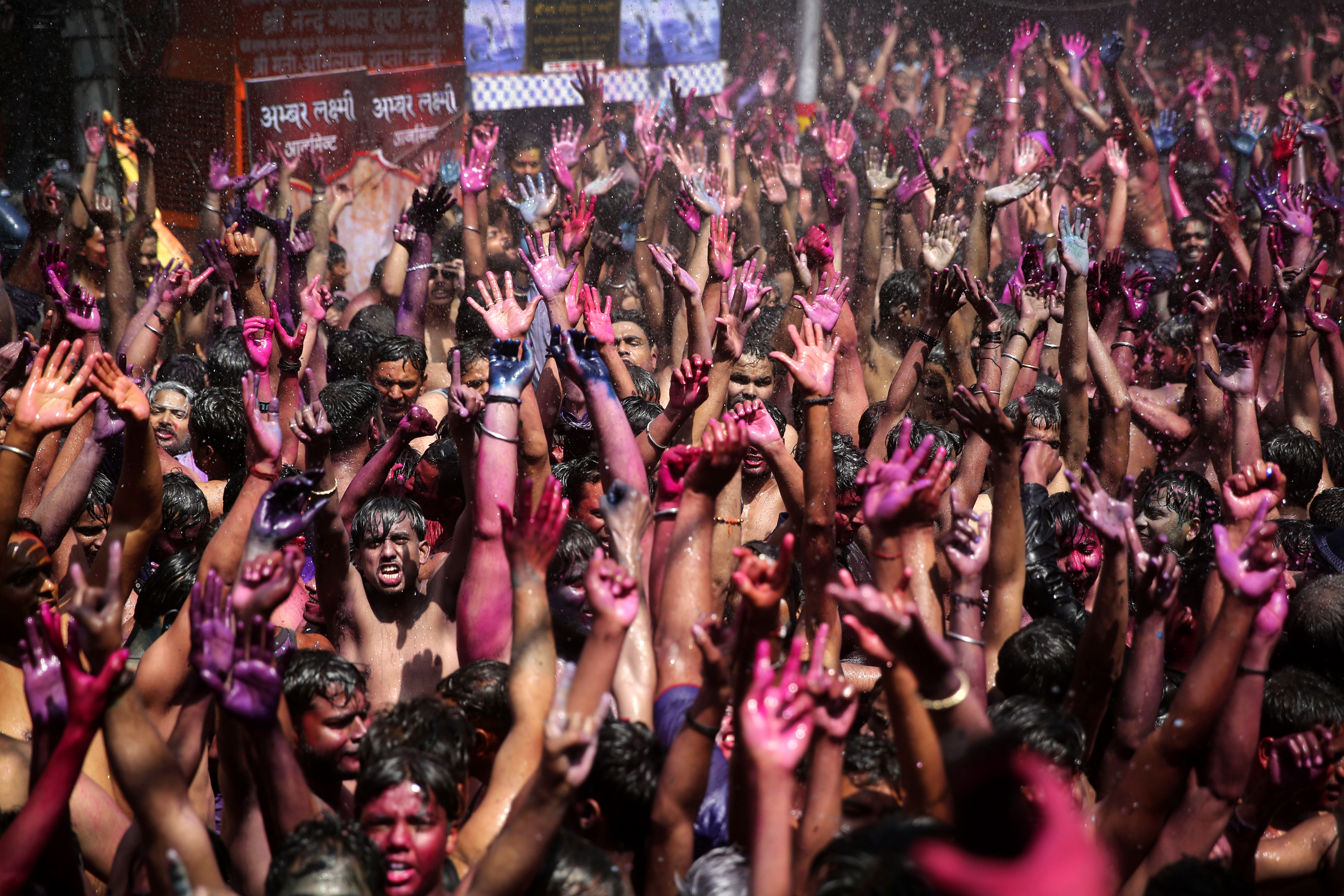 Indian revelers, faces smeared with colored powder, dance during Holi celebrations, or the Hindu festival of colors in Prayagraj - AP
