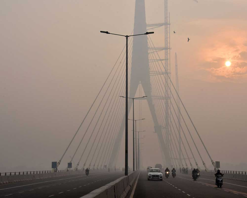 The sun is vaguely seen behind the Signature Bridge amid heavy smog, in New Delhi - PTI