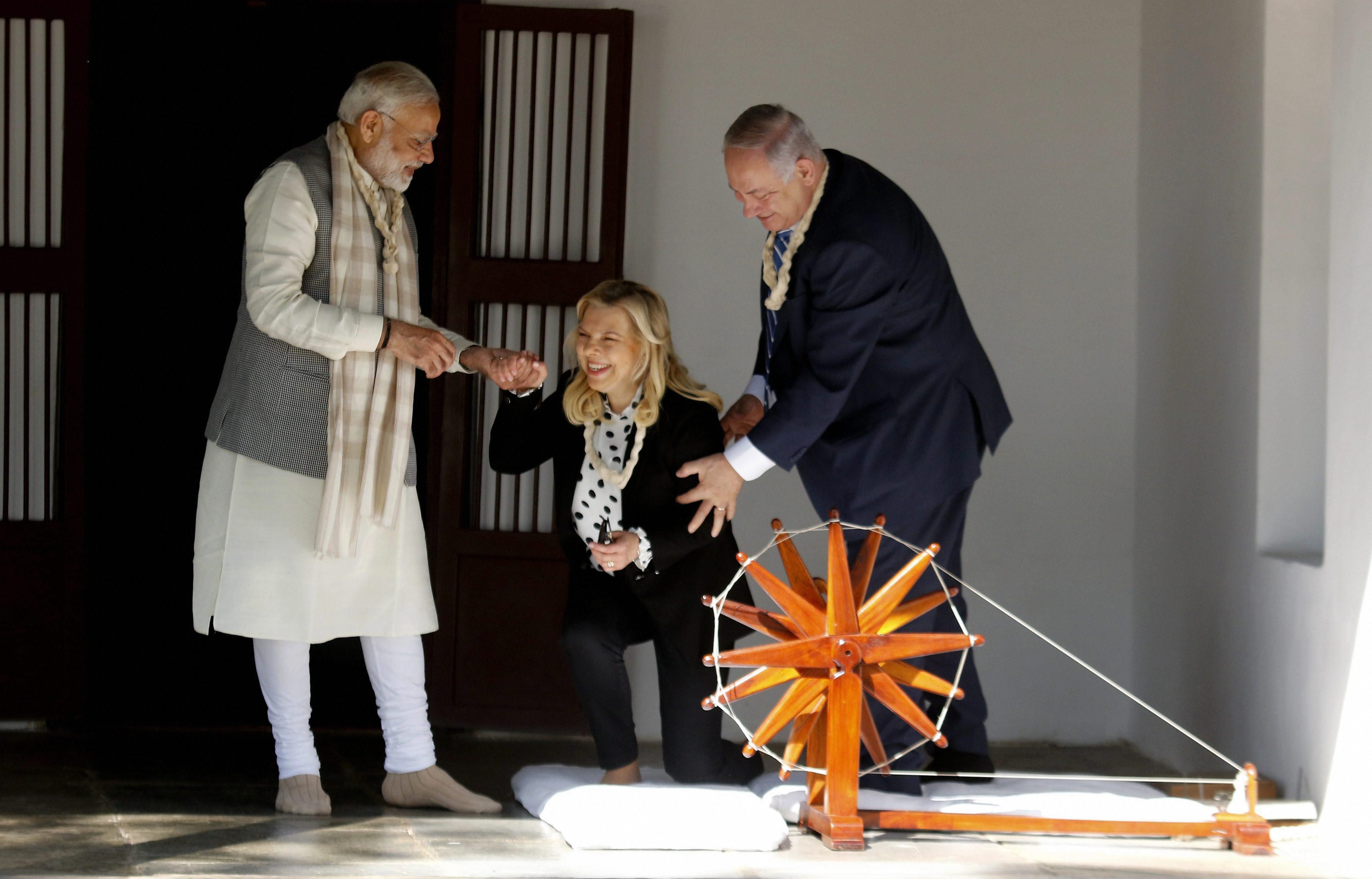 Prime Minister Narendra Modi and Israeli Prime Minister Benjamin Netanyahu assist Sara Netanyahu after she tried a traditional 'charkha' or spinning wheel during their visit to Sabarmati Ashram in Ahmedabad - PTI