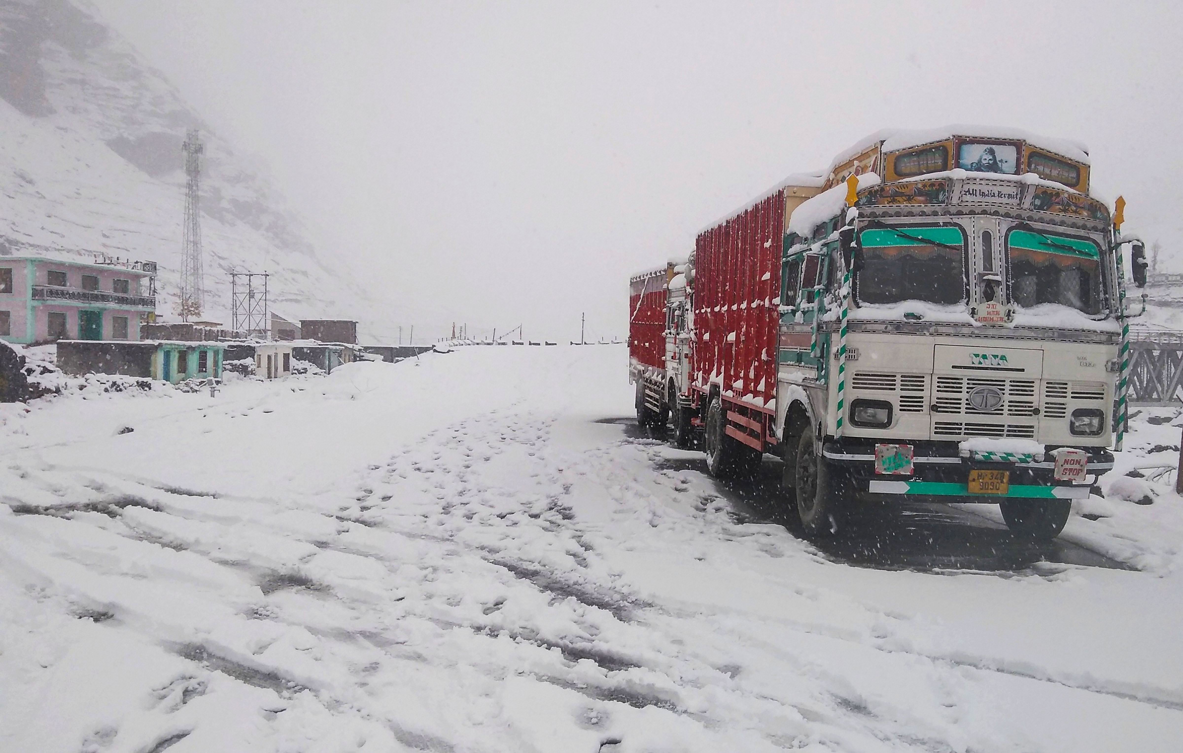 Trucks pave across a snow-laden pass on Manali-Leh route after fresh snowfall, in Manali -  PTI