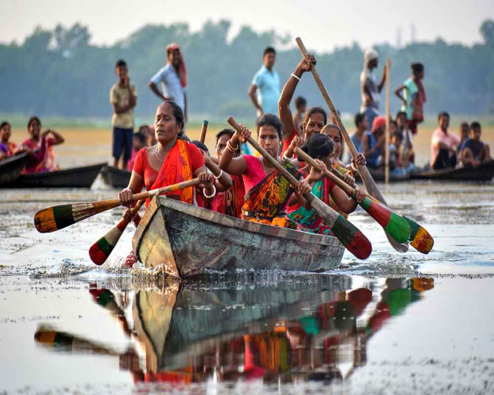 Oarswomen row their boat during the traditional annual boat race festival at Rudra Sagar Lake in Melaghar, 55 kms south-east of Agartala - PTI