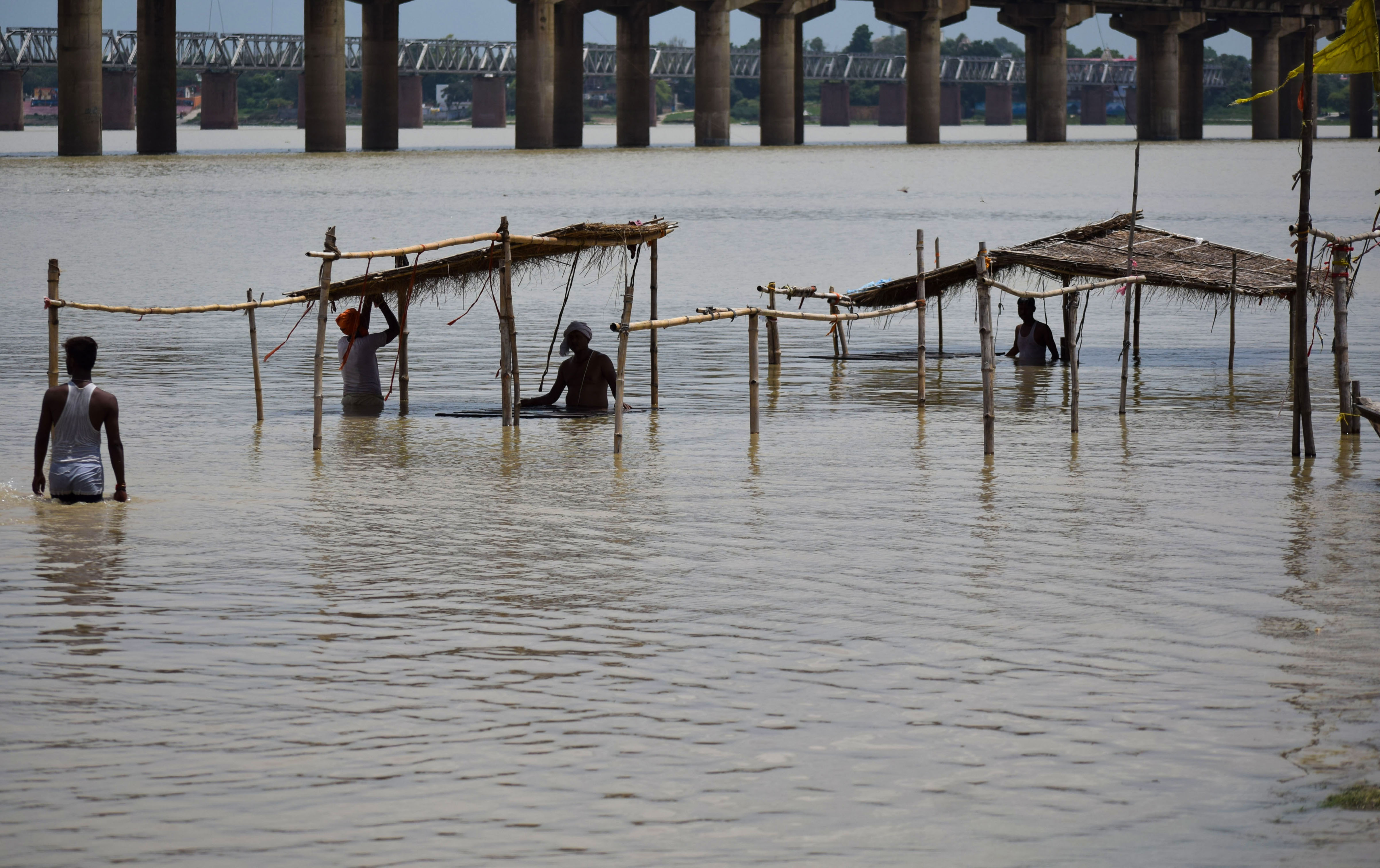 Priests shift with their cots from the flooded banks of the River Ganges, in Prayagraj - PTI