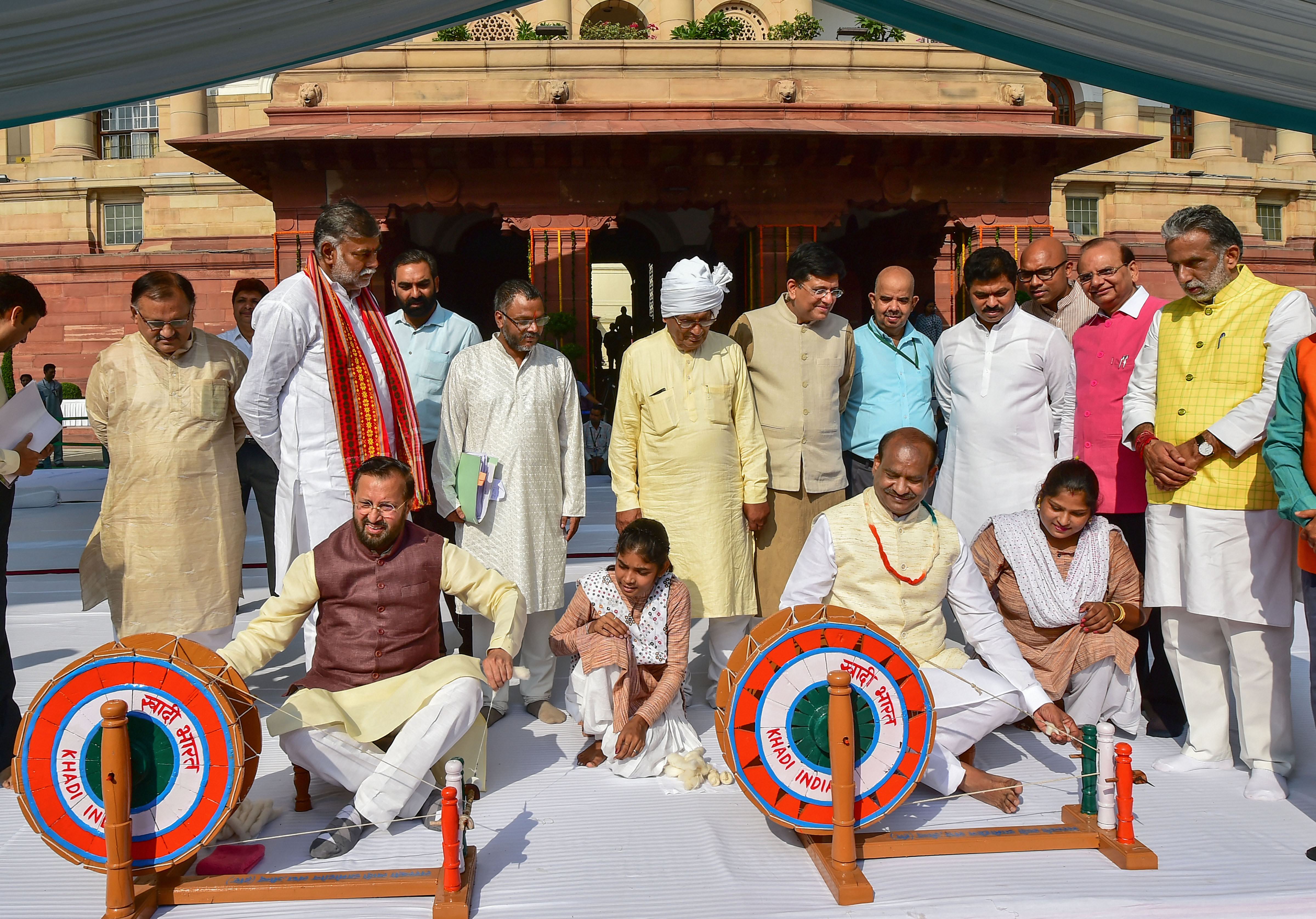 Lok Sabha Speaker Om Birla and  Union Ministers Piyush Goyal try their hands on a spinning wheel or 'charkha', during the 150th birth anniversary of Mahatma Gandhi - PTI