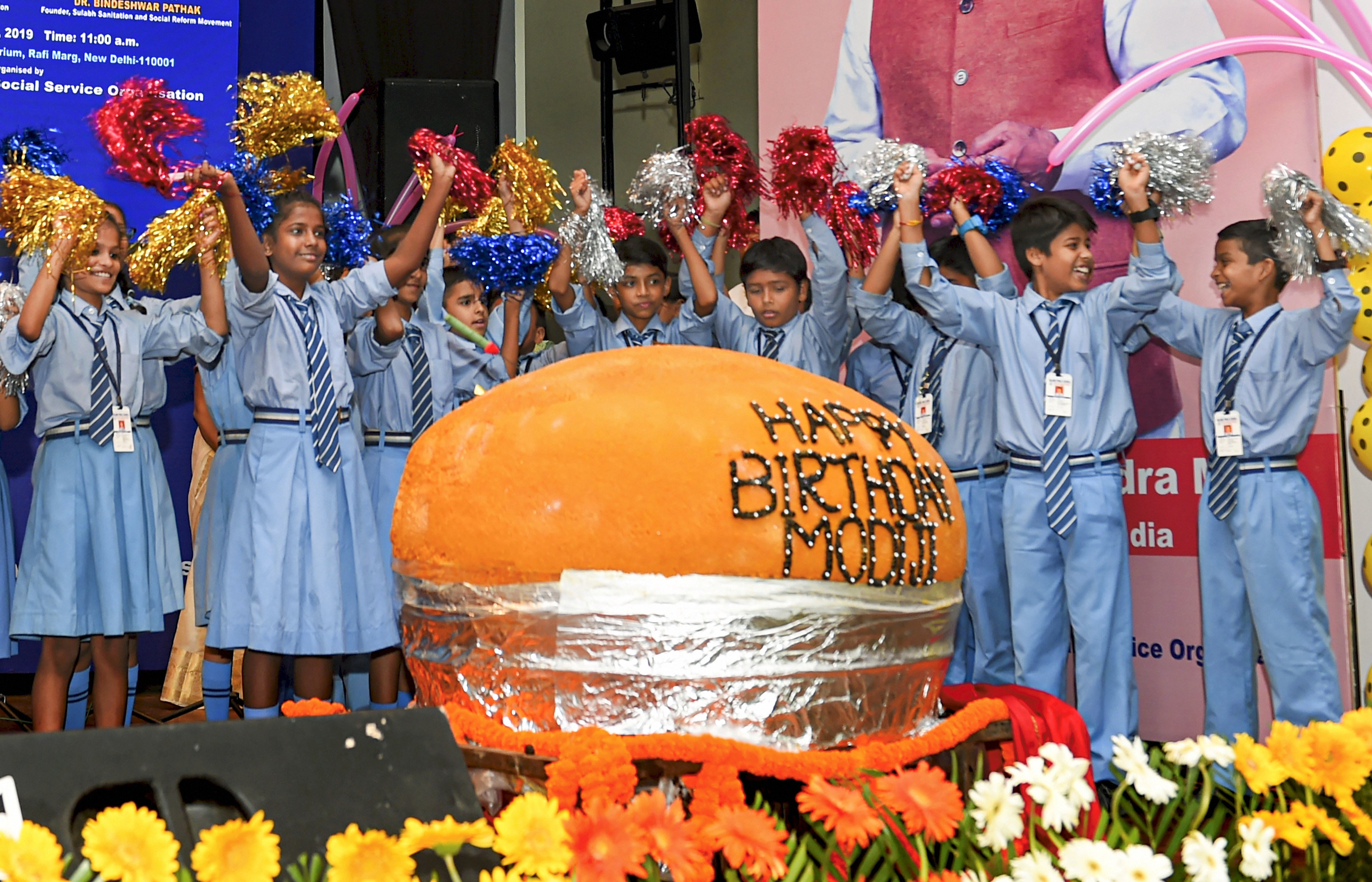 School children stand behind the 569 kg 'Laddu' specially made on 'Swachhta Diwas' to celebrate Prime Minister Narendra Modi's birthday - PTI
