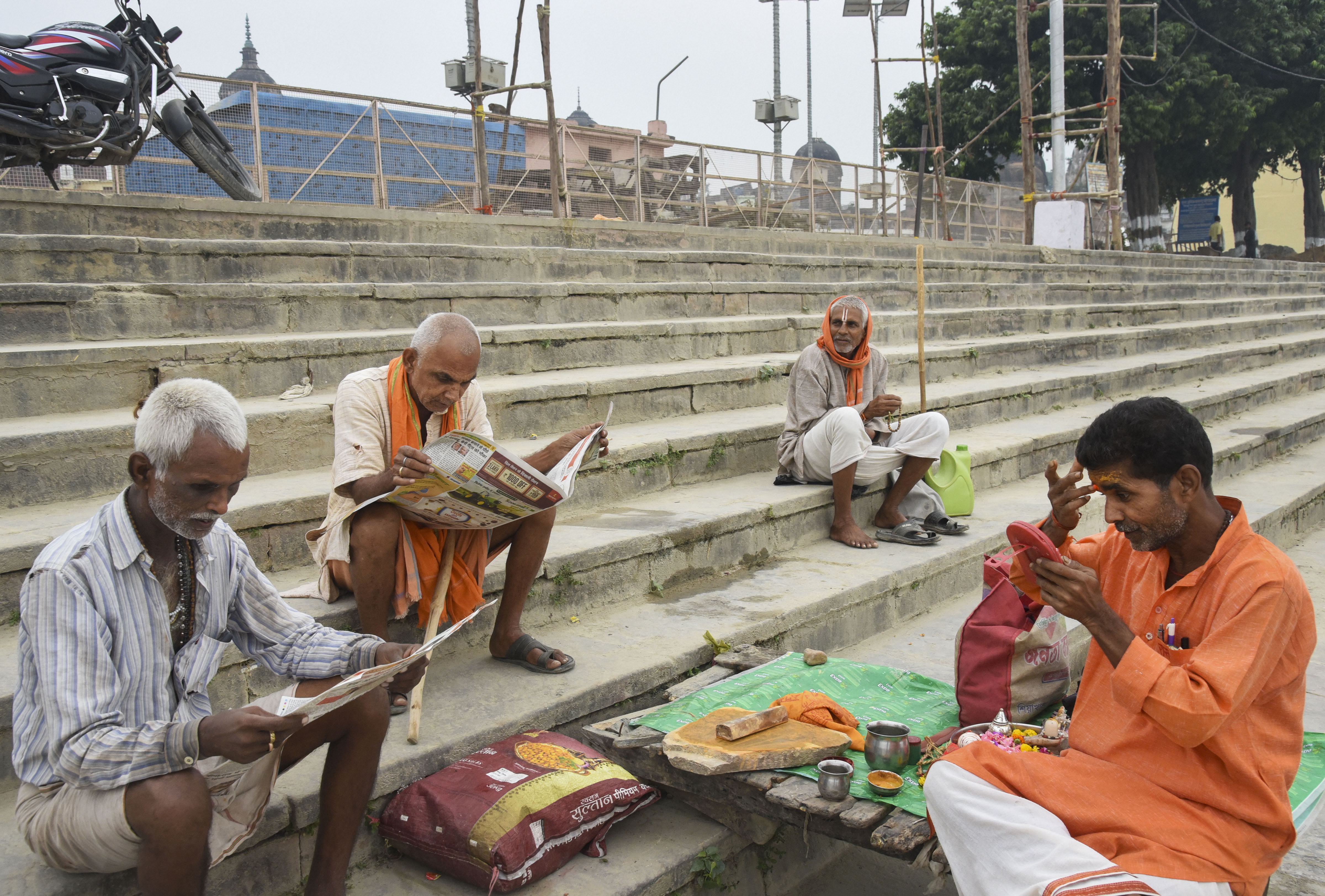 People read papers on the bank of river Saryu, in Ayodhya - PTI