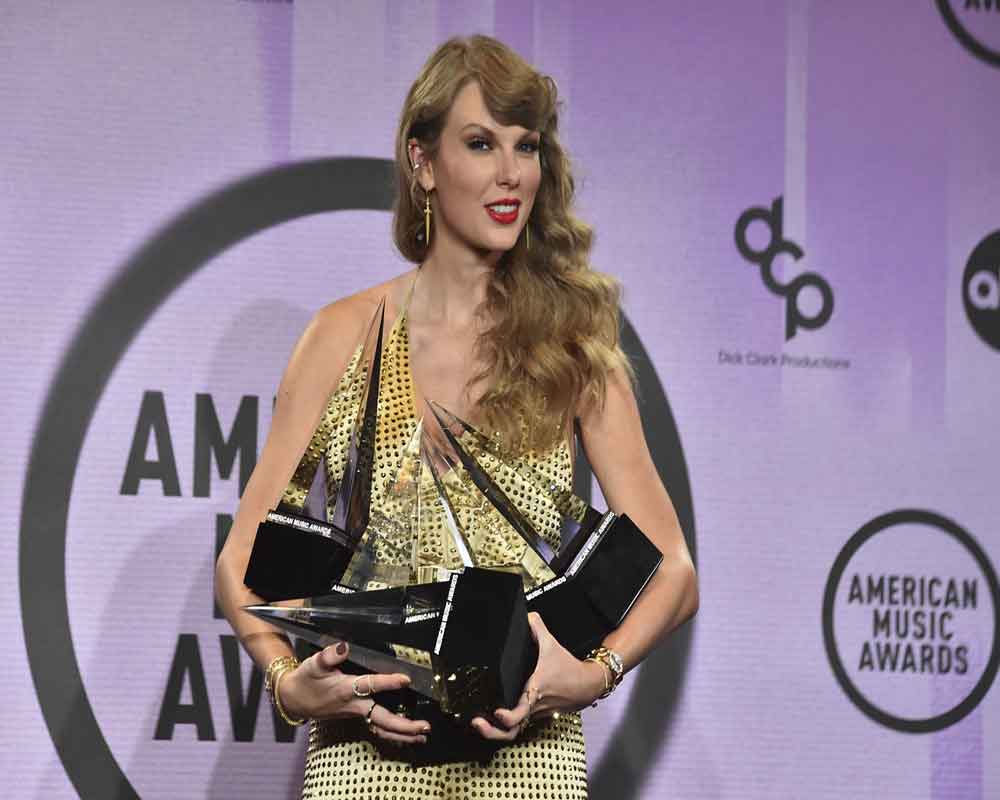 Taylor Swift poses in the press room with the awards for artist of the year, favorite music video for 