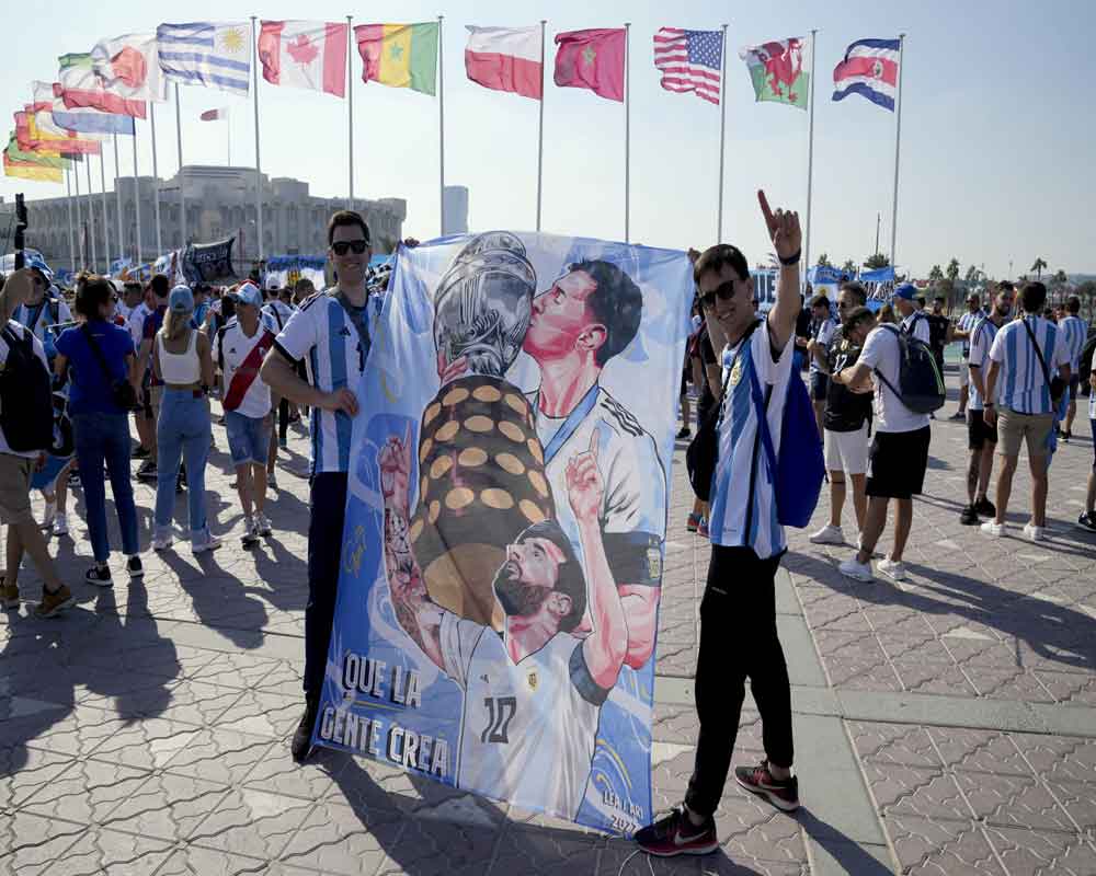 Two Argentina's soccer fans hold a flag with the image of soccer player Lionel Messi on the eve of the World Cup group C soccer match between Argentina and Saudi Arabia, in Doha, Nov. 21, 2022.